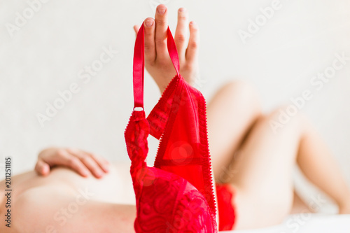 Nude girl holding a red bra in hand lying on the bed Stock Photo