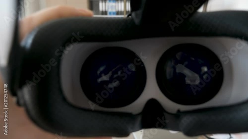 Man hands put a virtual reality headset on then takes it of. The footage is on a blurry background of an office