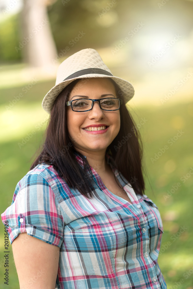 Portrait of beautiful young woman with hat in park, light effect