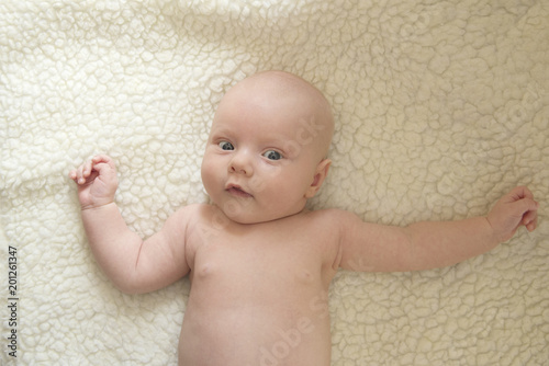 Portrait of a cute smiling newborn child against a white sheepskin