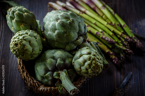 A still life of artichokes and asparagus on the rustic textured background Top view