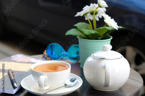 tea cup with kettle, sugar and plant on table in cafe outdoor
