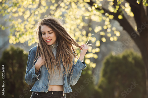 Smiling portrait of fashionable woman with dreadlocks at springtime