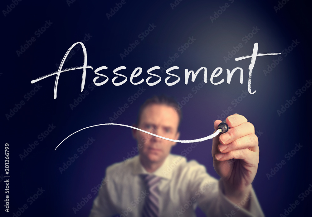 A businessman writing a Assessment concept with a white pen on a clear screen. A businessman writing a Assessment concept with a white pen on a clear screen.