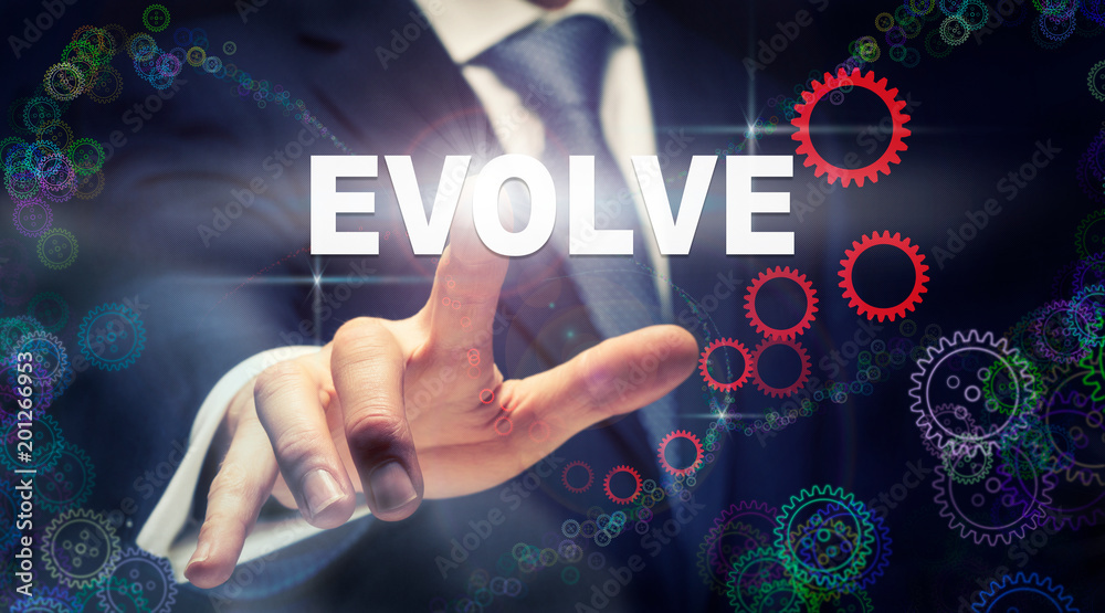 A businessman pressing a Evolve business concept on a graphical display of cogs A businessman pressing a Evolve business concept on a graphical display of cogs