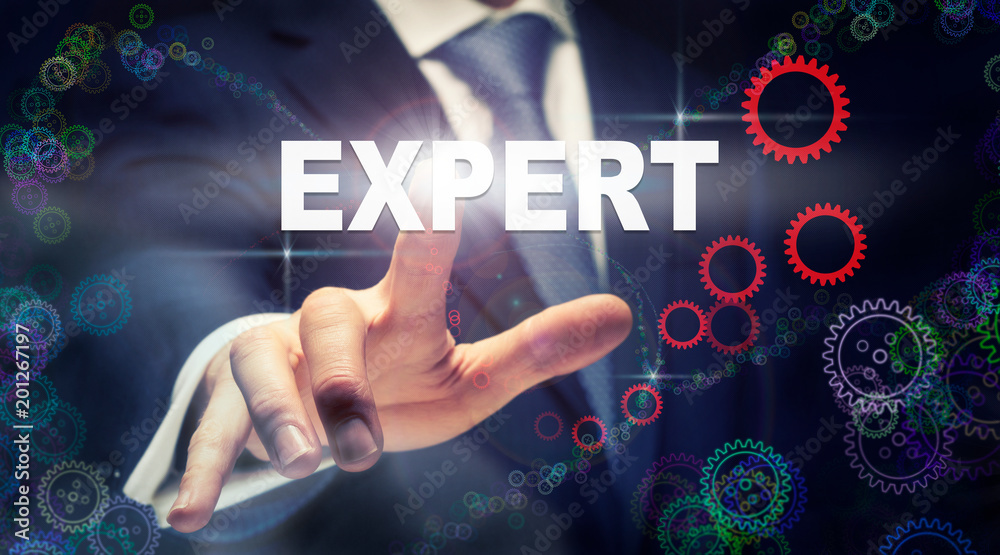 A businessman pressing a Expert business concept on a graphical display of cogs A businessman pressing a Expert business concept on a graphical display of cogs