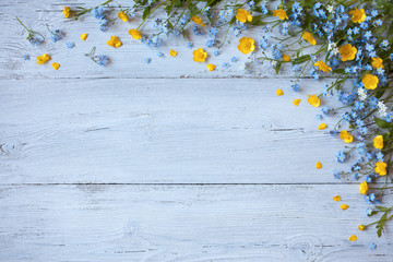 Spring and summer flowers forget-me-nots, buttercups on a wooden background