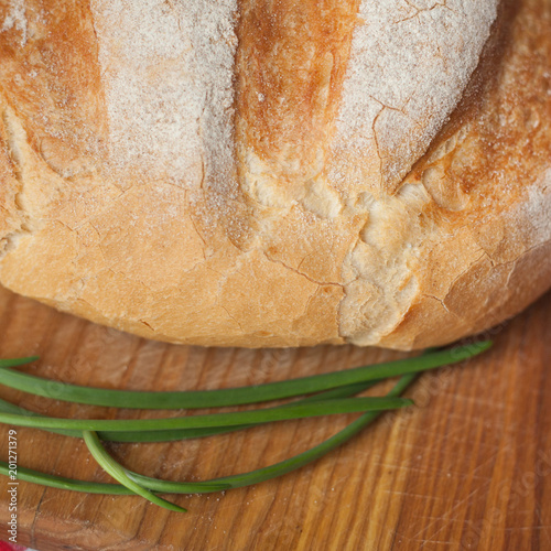 Crusty loaf at top view are on a wood table with green onion photo