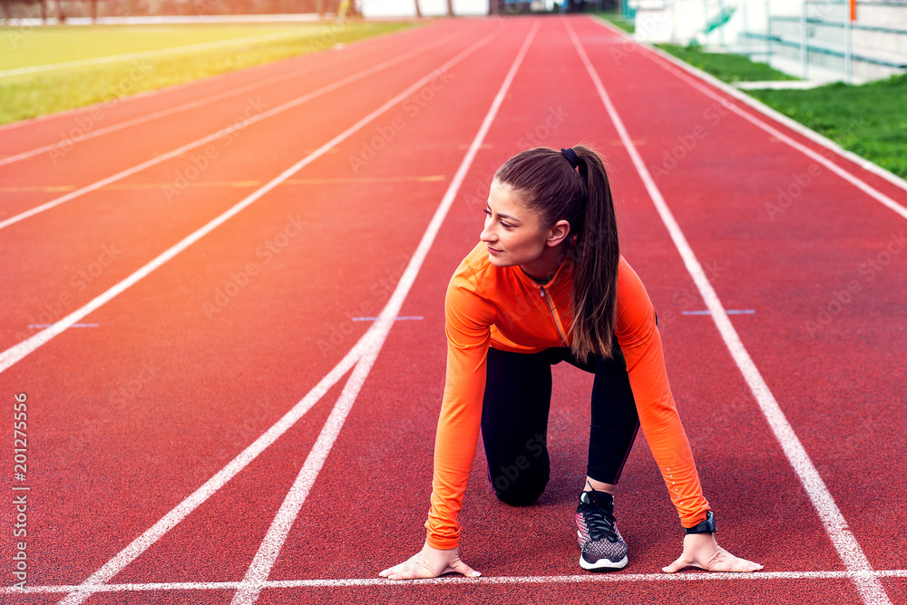 Fototapeta premium Focused sports women in running start position on racetrack