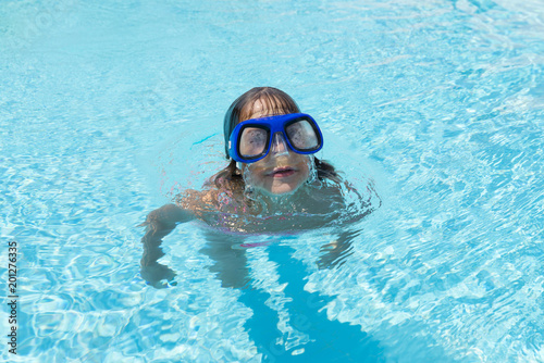 Little girl with blue diving glasses in an outdoor pool