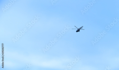The military helicopter in the blue sky above me high. High in the sky aviation.
