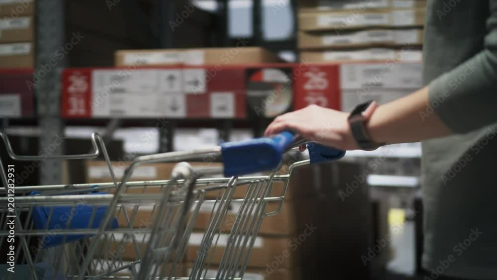 woman is making purchases in store. Female hands are driving a shopping trolley in hardware store woman is making purchases in store. Female hands are driving a shopping trolley in hardware store
