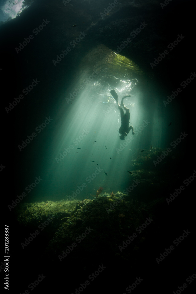 Diver in Sunlit Underwater Cavern in Raja Ampat