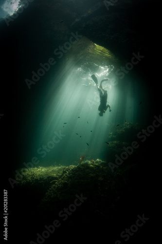 Diver in Sunlit Underwater Cavern in Raja Ampat