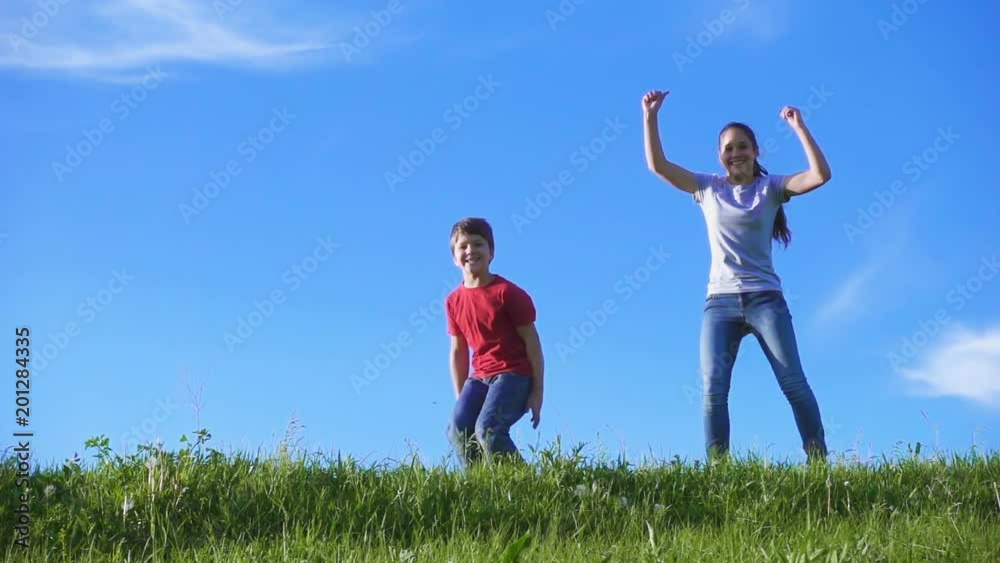 Happy kids jumping together on green grass hill against blue sky Happy kids jumping together on green grass hill against blue sky