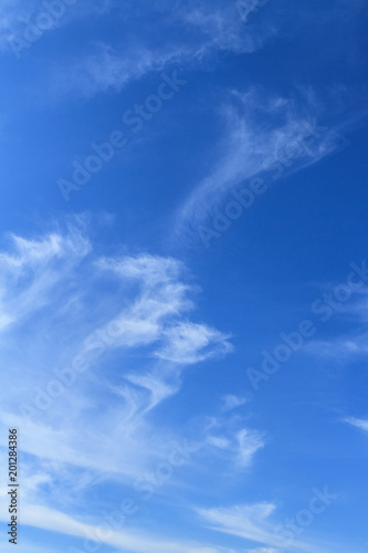 Bodies of unique delicate painterly diffused thin white cloud patterns on a blue sky nature background