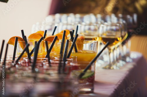 Beautiful row line of different colored alcohol cocktails on a party on decorated catering banquet table
