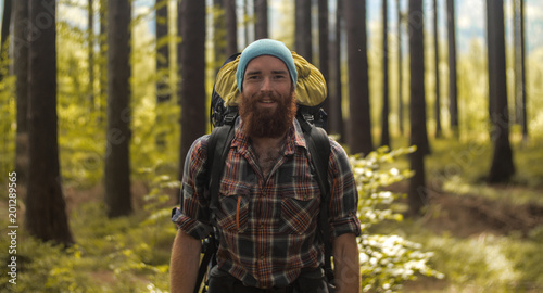 portrait of a caucasian male hiker standing outdoors in a forest with a backpack