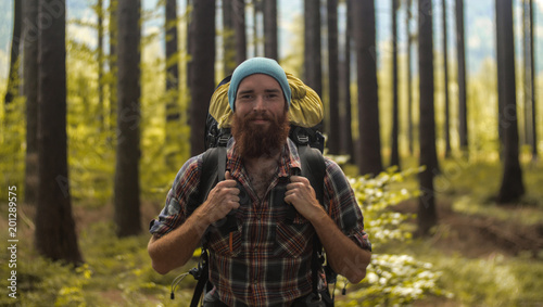 portrait of a caucasian male hiker standing outdoors in a forest with a backpack