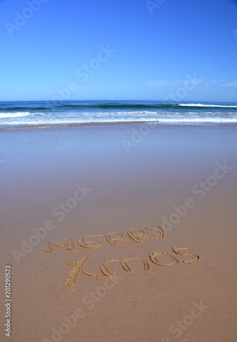 Merry Xmas written on sand at sunset. Merry Christmas lettering on the beach. "Merry Xmas" drawn on sand on a beach closeup shot. Merry Christmas written in sand on tropical beach.