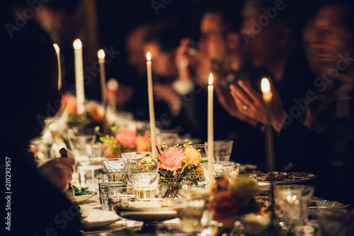 People enjoy a family dinner with candles. Big table served with food and beverages. photo