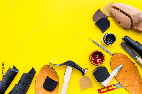 Clobber tools. Hummer, awl, knife, sciccors, wooden shoe, paint and leather. Yellow background top view space for text