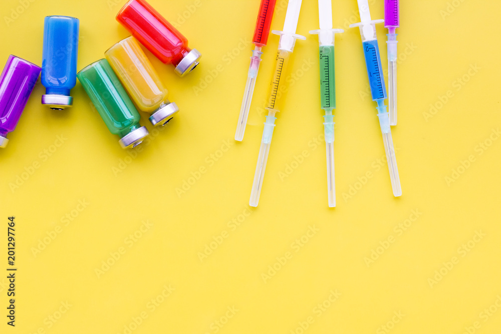 Medical injection Syringe and bottle with remedy on yellow background top view copy space