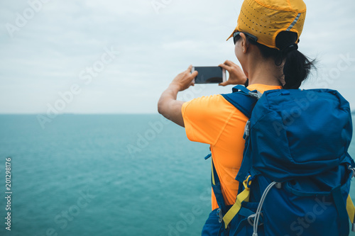  woman hiker taking photo with smartphone  on seaside photo