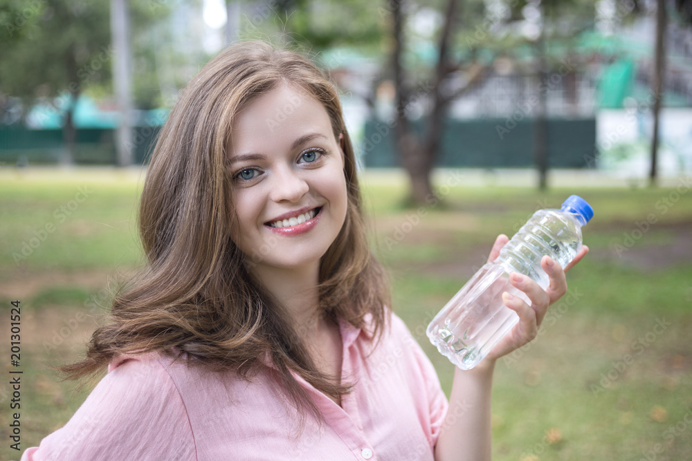 Young caucasian woman holding plastic bottle with water in her hand Young caucasian woman holding plastic bottle with water in her hand