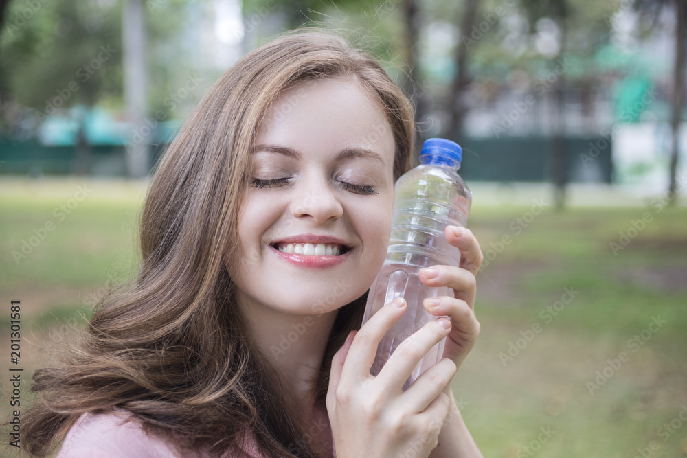Young caucasian woman holding plastic bottle with water in her hand Young caucasian woman holding plastic bottle with water in her hand