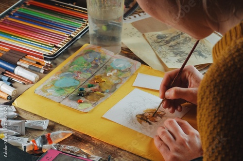 female artist painter woman paiting a watercolor picture of a bear, indoors, cozy wooden cabin