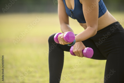 woman in sportswear exercising with dumbbells