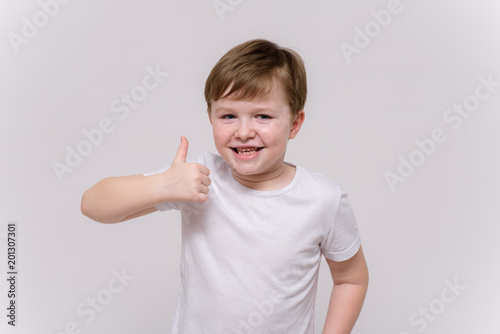 cute boy aged 6 years shows on a white background in different poses different emotions