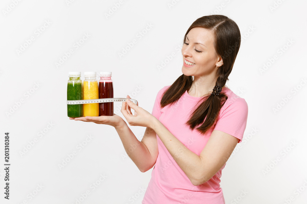 Woman holds row of green, red, yellow detox smoothies in bottles, measure tape isolated on white background. Proper nutrition, vegetarian drink, healthy lifestyle, dieting concept. Copy space, flack. Woman holds row of green, red, yellow detox smoothies in bottles, measure tape isolated on white background. Proper nutrition, vegetarian drink, healthy lifestyle, dieting concept. Copy space, flack.