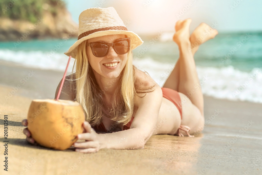 Portrait of smiling young woman in sunglasses and summer hat lay