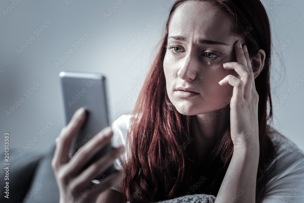 No missed call. Dreary lonely gloomy woman crying while touching temples  and staring at phone screen Stock Photo | Adobe Stock