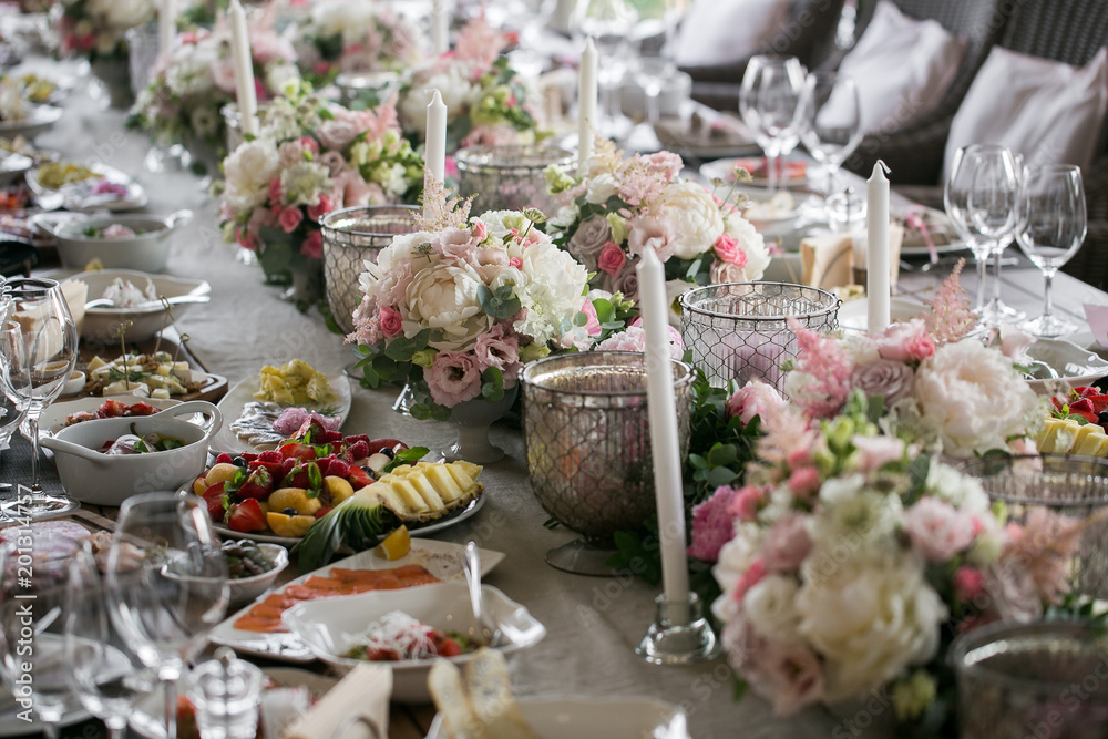 Fototapeta premium Garland of flowers and greenery for table decoration. Luxury wedding reception in restaurant. Stylish decor and adorning. Tables served with beautiful dishes and delicious food