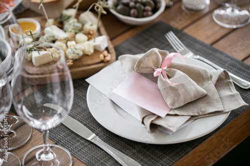Plate with linen napkin and pouch gift. Luxury wedding reception in restaurant. Stylish decor and adorning. Tables served with beautiful dishes and delicious food