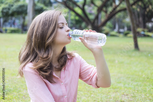 Young caucasian woman drinks water from the bottle