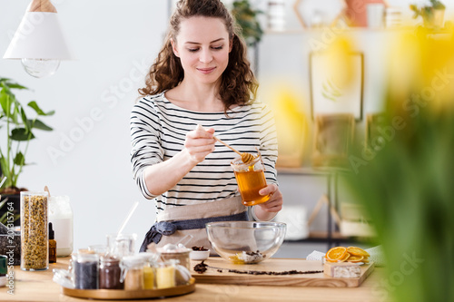 Smiling woman pouring honey photo