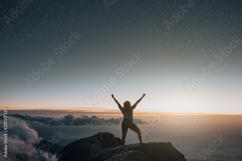 Silhouette woman raising arms above clouds