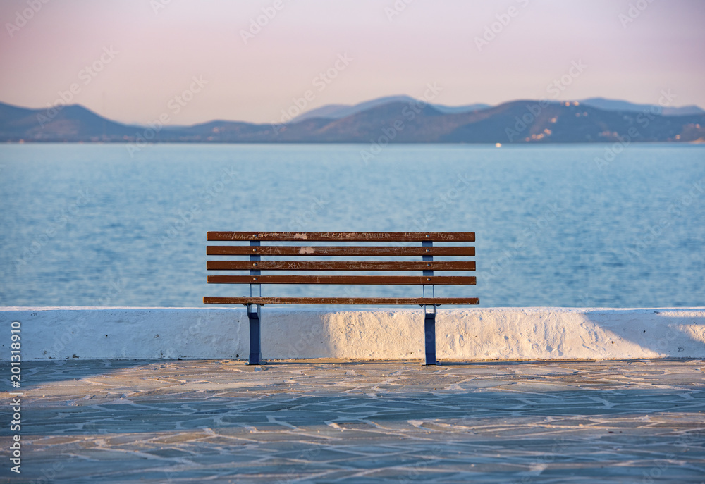 sunset and bench in Rafina city with Aegean sea at the background sunset and bench in Rafina city with Aegean sea at the background