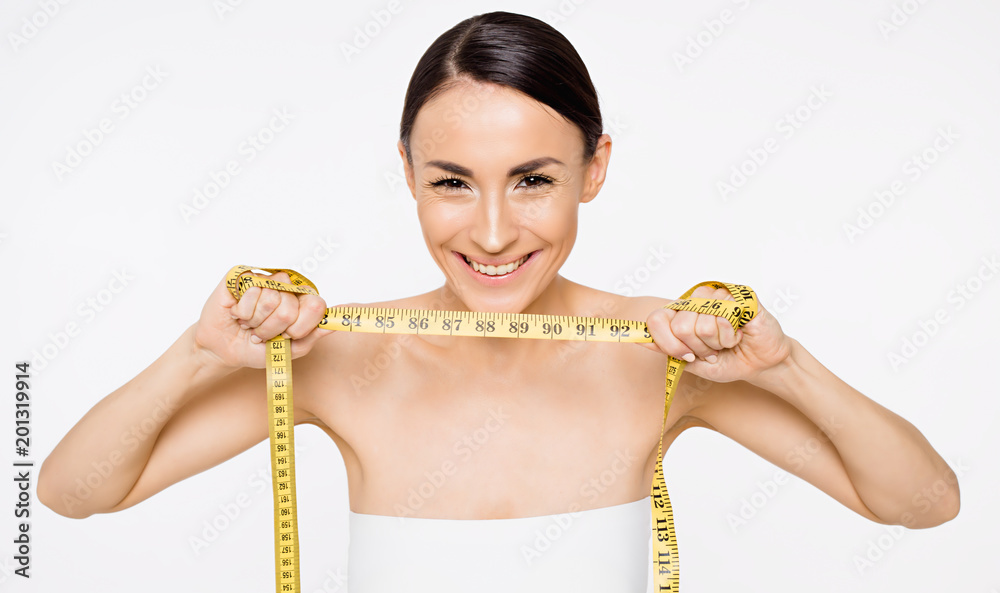 No excess weight. Beautiful smiling slender woman shows a tape to measure the waist in the camera. No excess weight. Beautiful smiling slender woman shows a tape to measure the waist in the camera.