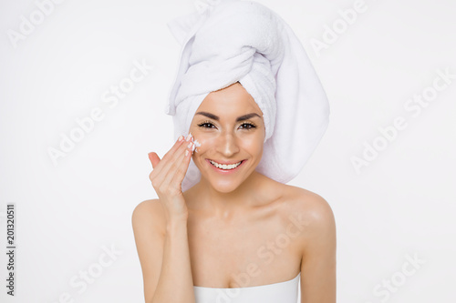 Face cream. Skin care. Beautiful smiling woman with a towel on her head after showering. Cosmetology. Beauty & Spa