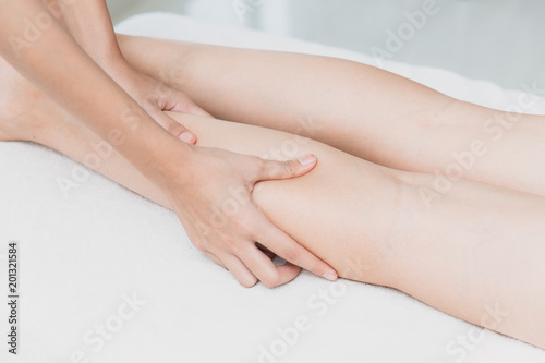 osteopath hand squeezing leg massage and spa on female calf muscle