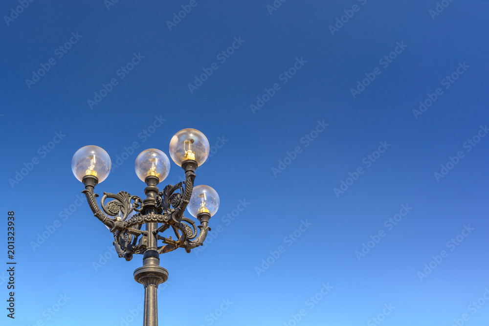 a lamppost with glass shades against the blue sky. copyspace