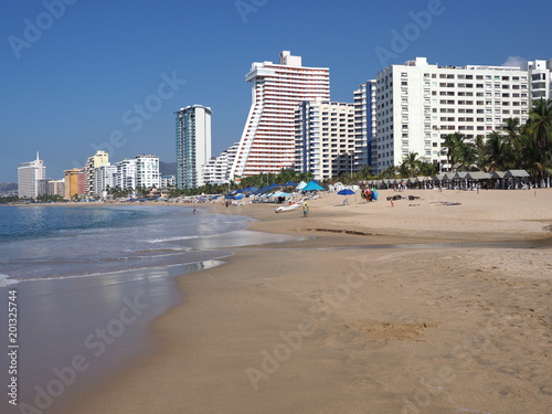 Panorama of white hotel buildings on beauty sandy beach at bay of Pacific Ocean at ACAPULCO city in Mexico with tourists