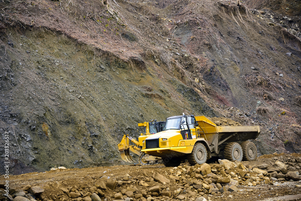 Heavy articulated dump truck work at a huge dam construction site Heavy articulated dump truck work at a huge dam construction site