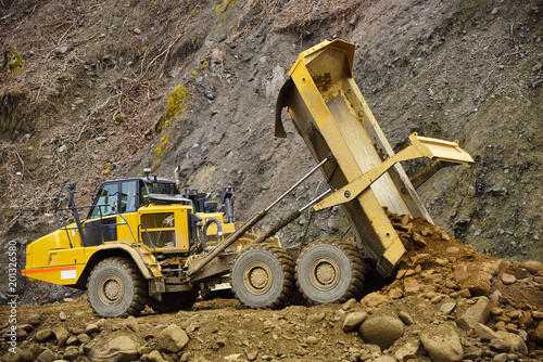 Heavy articulated dump truck work at a huge dam construction site