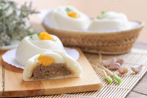 Chinese white steamed bun known as Dim Sum or salapao filled with minced pork seasoning decorate with hard boiled egg and coriander ready to serve for breakfast or lunch. Homemade food concept.